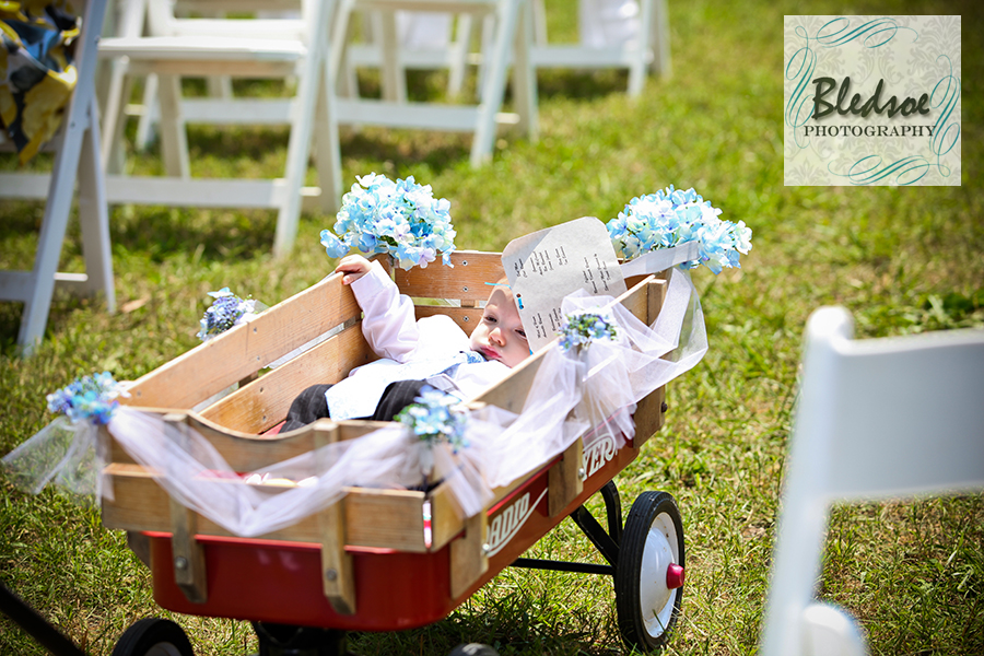 Ring bearer riding in a wagon down the aisle at Dara's Garden.