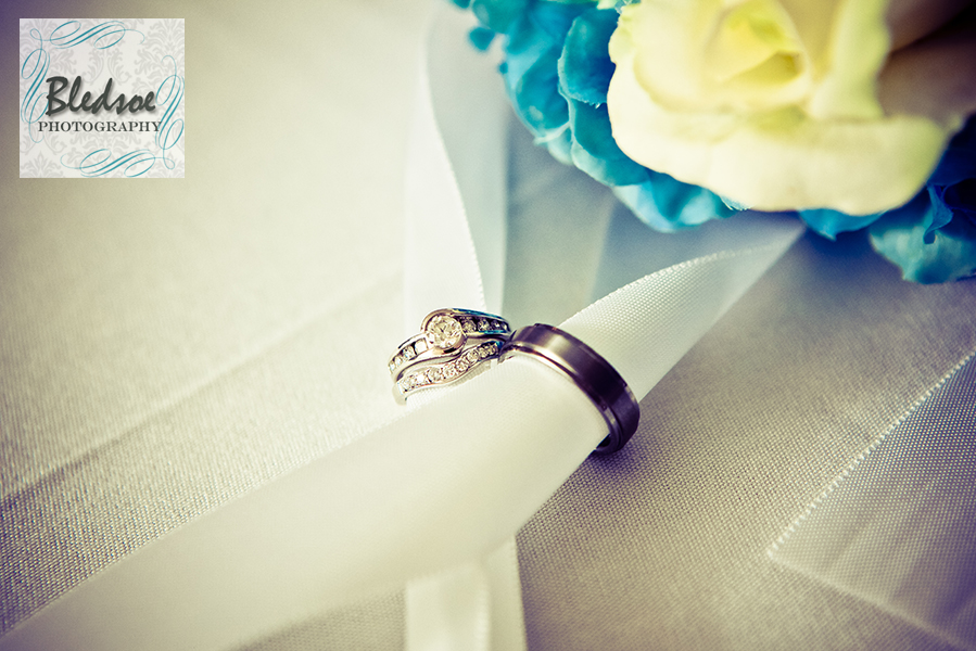 Close up shot of wedding rings entwined in bride's bouquet ribbon.