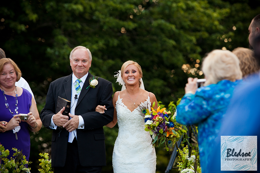 Bride smiling at groom as she walks down the aisle at Pick Inn. © Bledsoe Photography