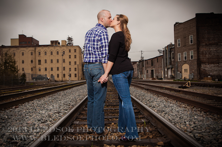 Knoxville engagement photo session in the Old City, couple kissing on the railroad tracks © Bledsoe Photography