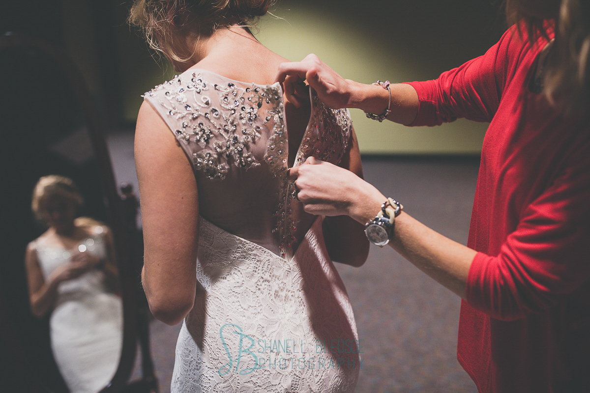 Sister zipping bride's wedding dress