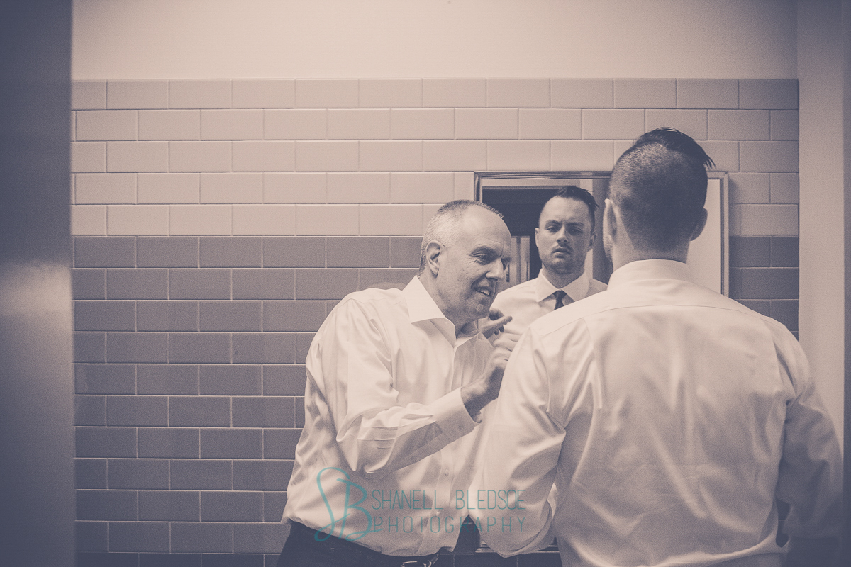 Father typing groom's tie, mirror reflection