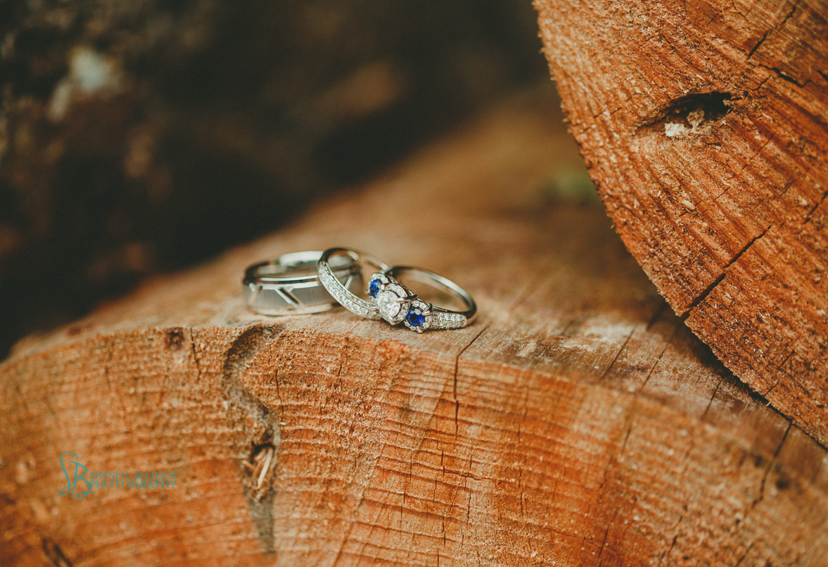 wedding bands on chopped wood, sapphire engagement ring