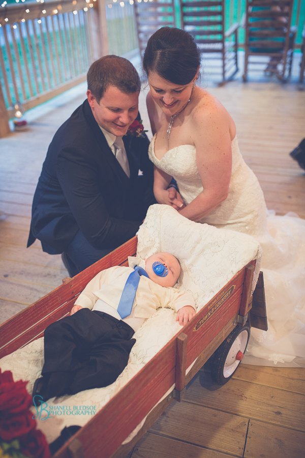 bride and groom watch sleeping son in red wagon