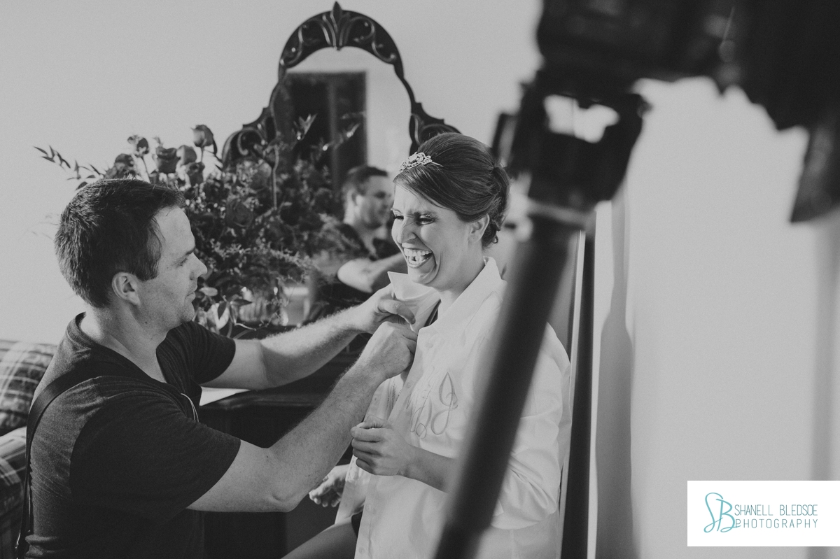 Videographer putting mic on bride, Milestone Pictures