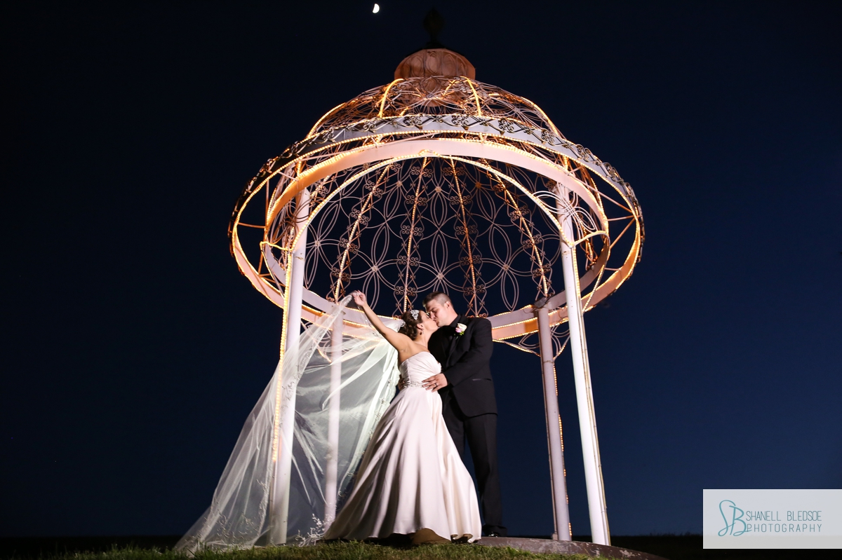 Night photo of bride and groom kissing inside gazebo at The Stables in LaFollette, TN