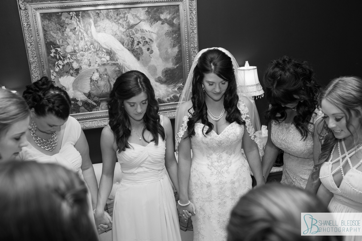 Bride praying with bridesmaids before wedding ceremony