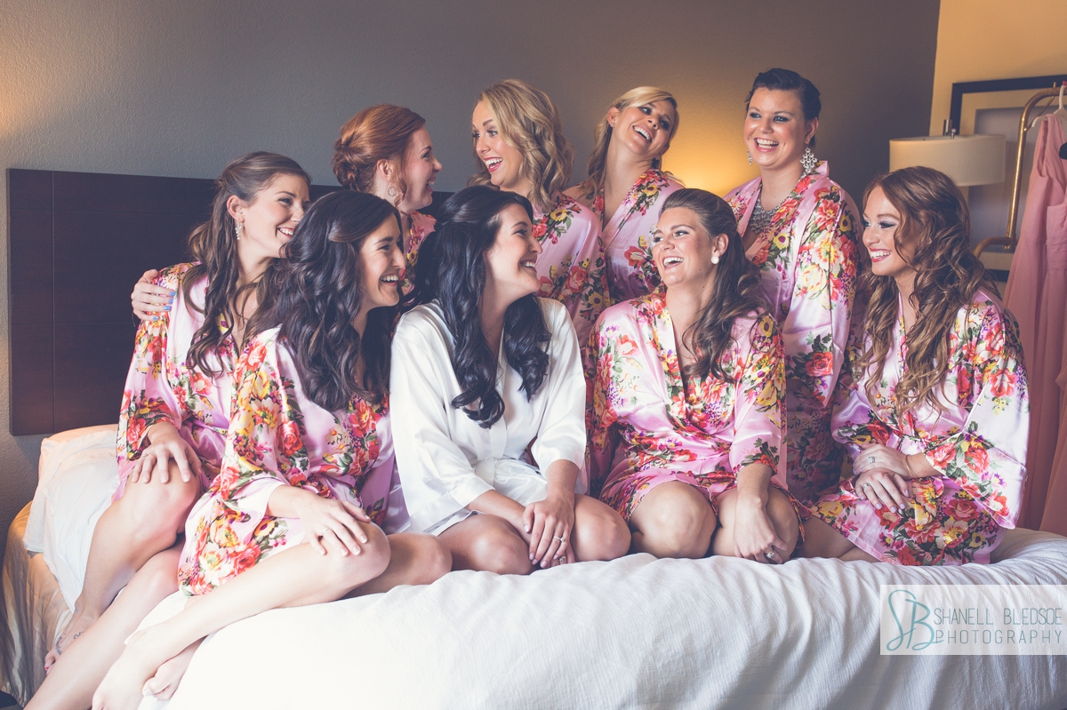bride and bridesmaids in floral pink robes wedding on hotel bed