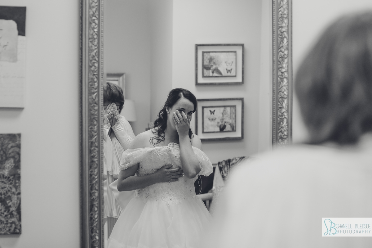 crying bride in mirror putting on wedding dress