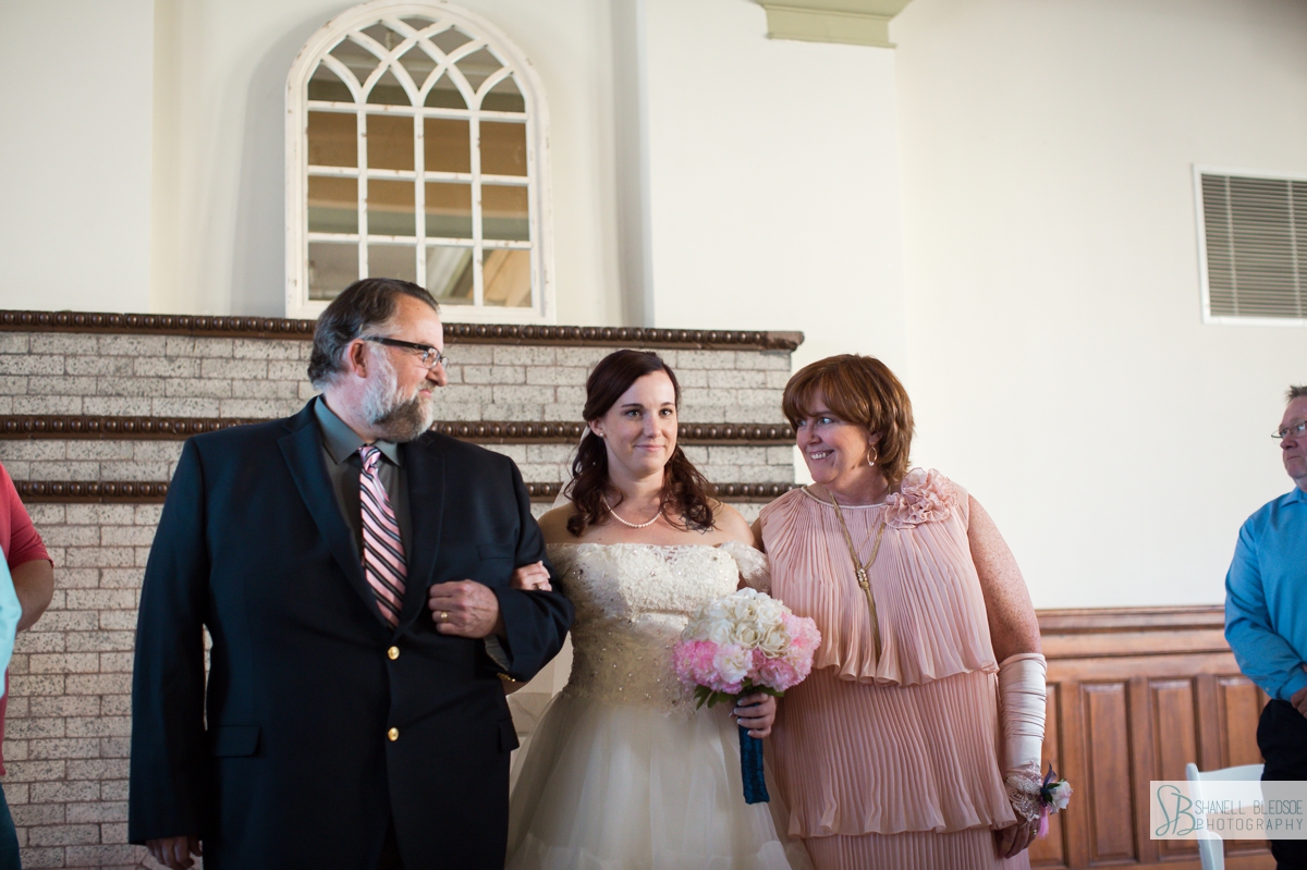 mother and father walking bride down the aisle at historic southern railway station