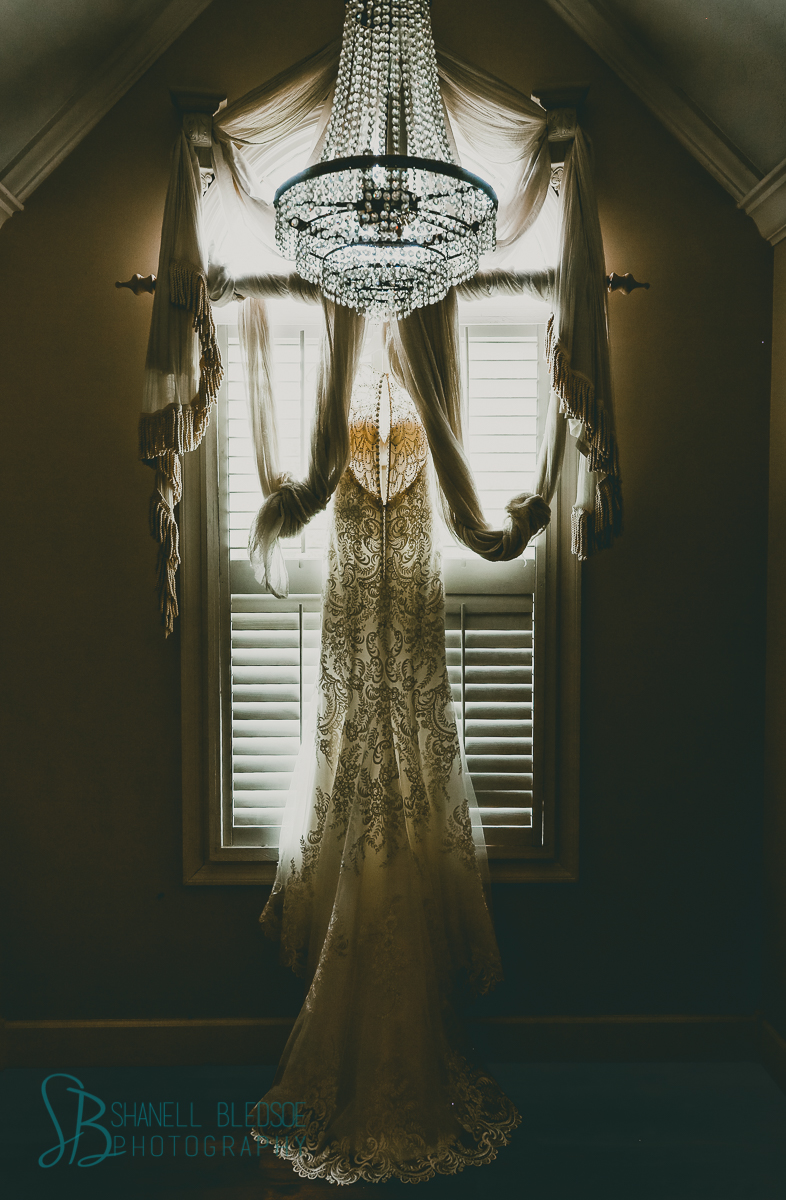 lace wedding dress in arched window with chandelier