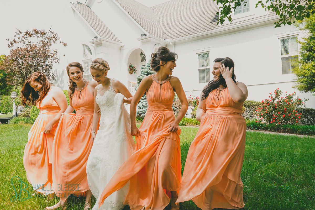bride and bridesmaids in peach coral dresses blowing in the wind