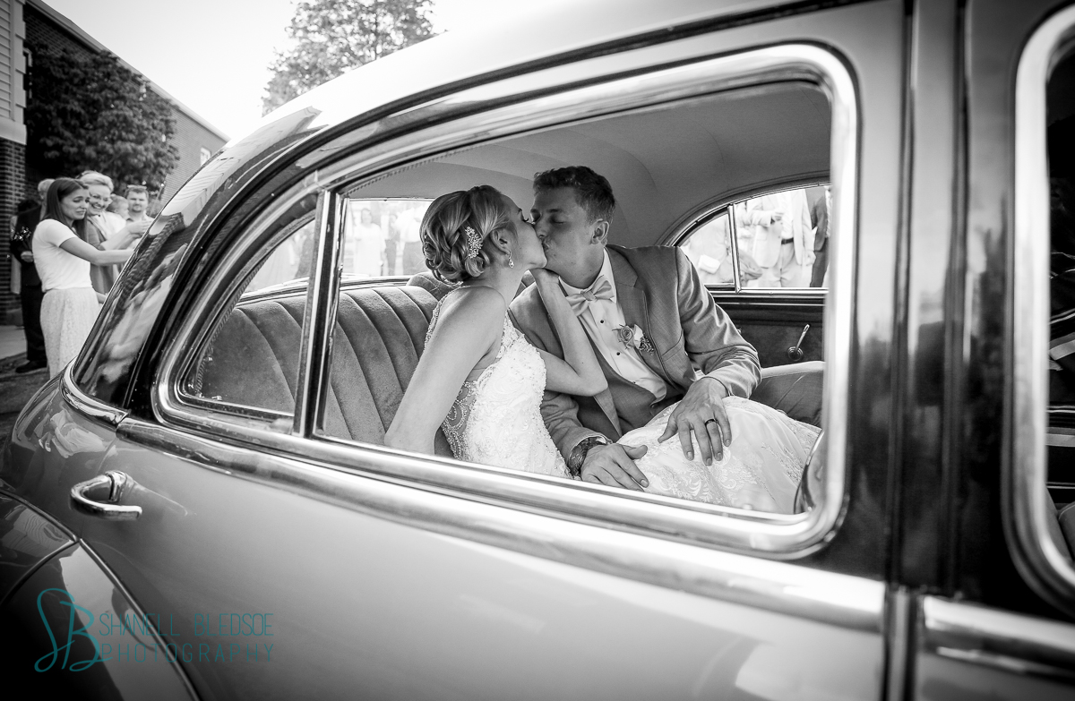 bride and groom kissing in vintage Buick Eight
