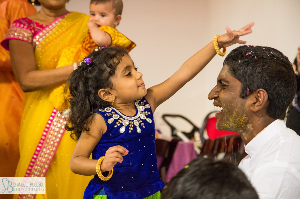little girl sprinkling rice over indian groom's head at haldi ceremony in nashville