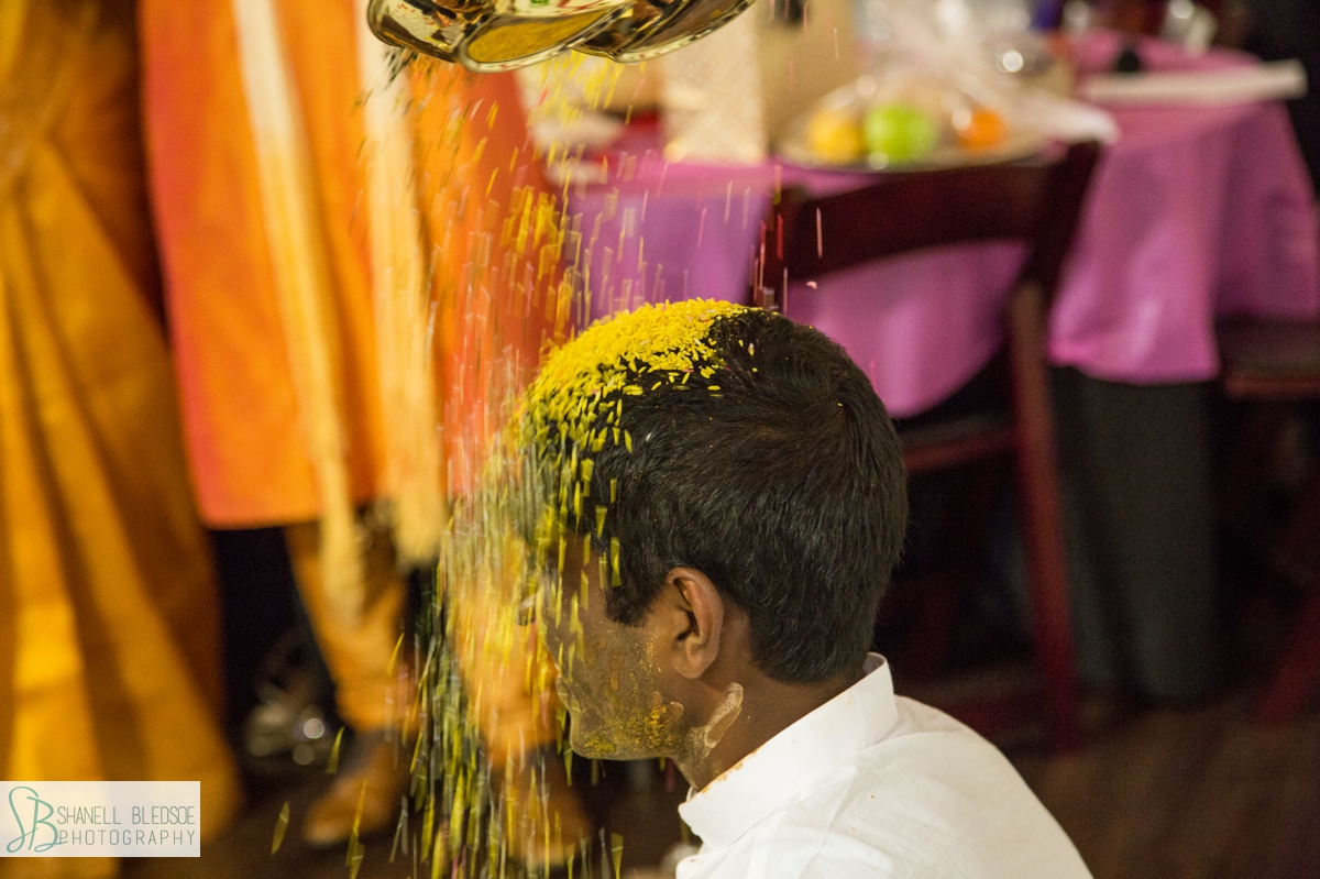 rice saffron poured over Indian groom's head at Haldi