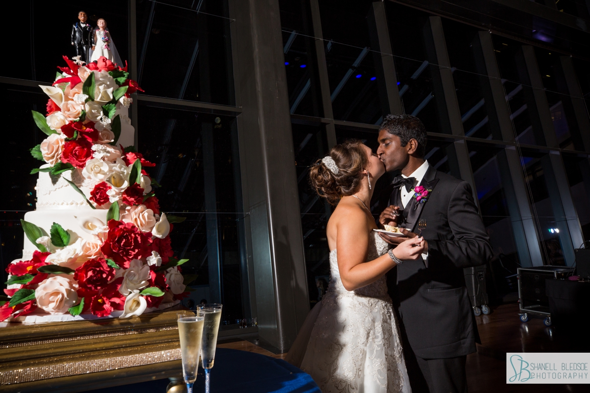 bride and groom kiss cut the cake at country music hall of fame wedding reception