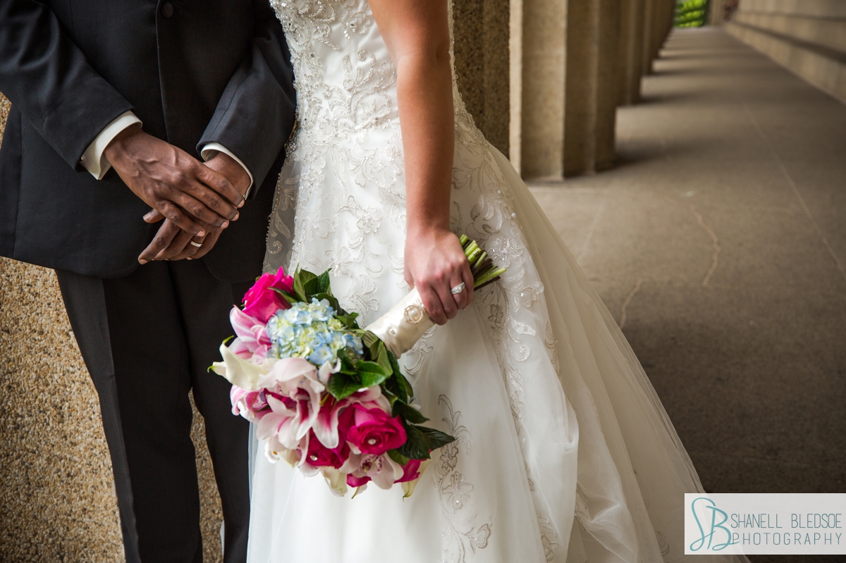 closeup of bride and grooms hands with stargazer lily bouquet at the parthenon in nashville