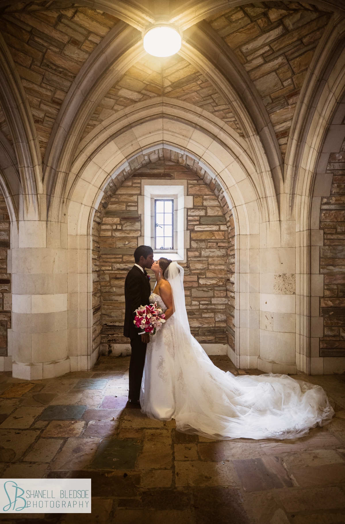 portrait of bride and groom under arch at Scarritt Bennett in Nashville with pink stargazer lily bouquet