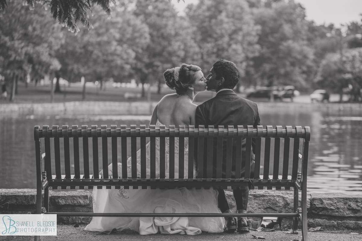 bride and groom kiss on park bench at Centennial Park in Nashville TN