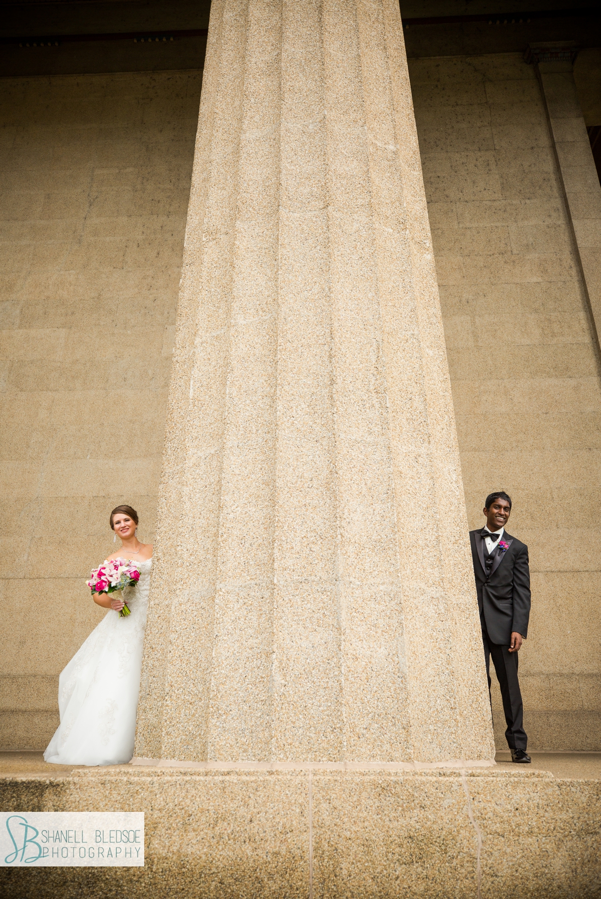 bride and grooms peek around columns at the parthenon in nashville