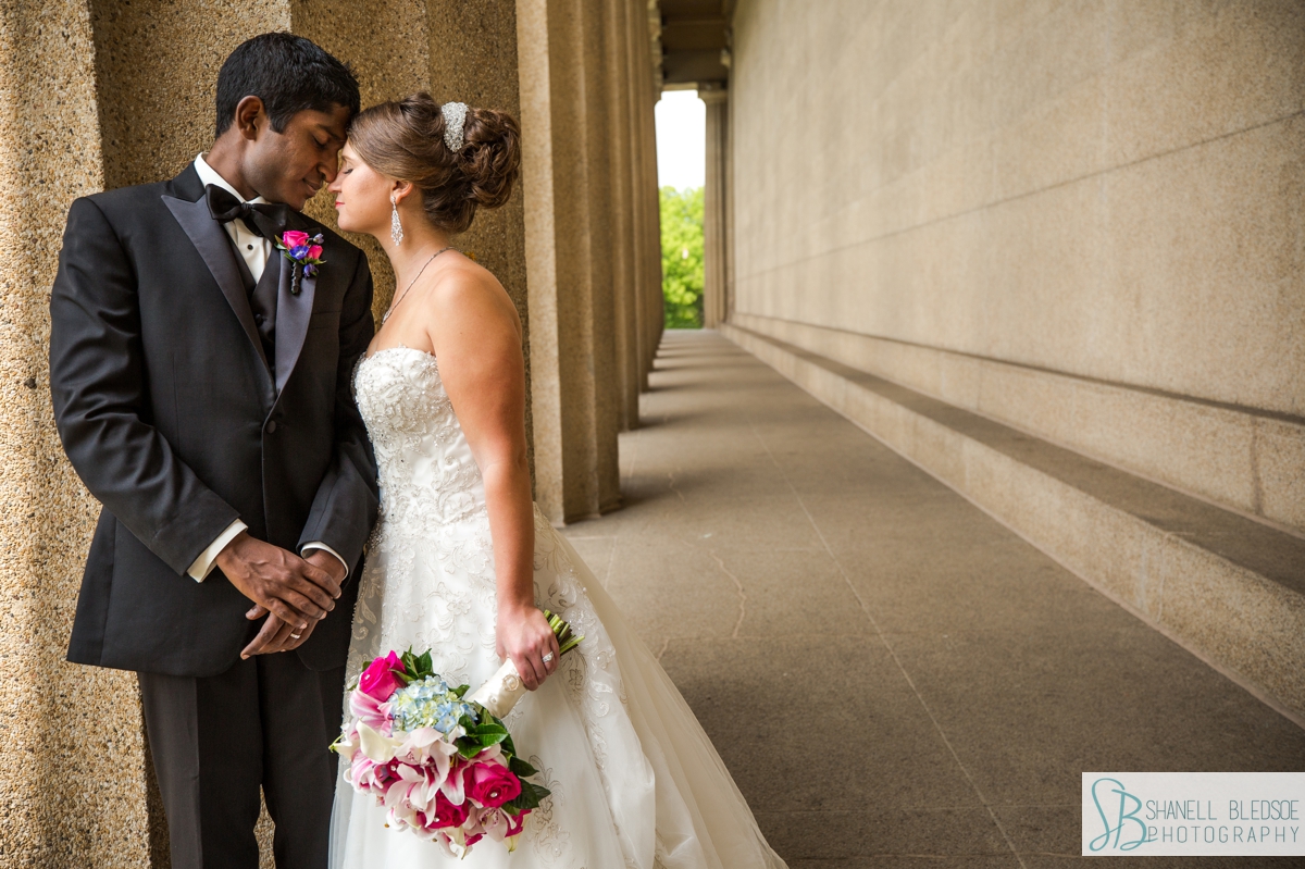 bride and groom pose in the columns at the parthenon in nashville