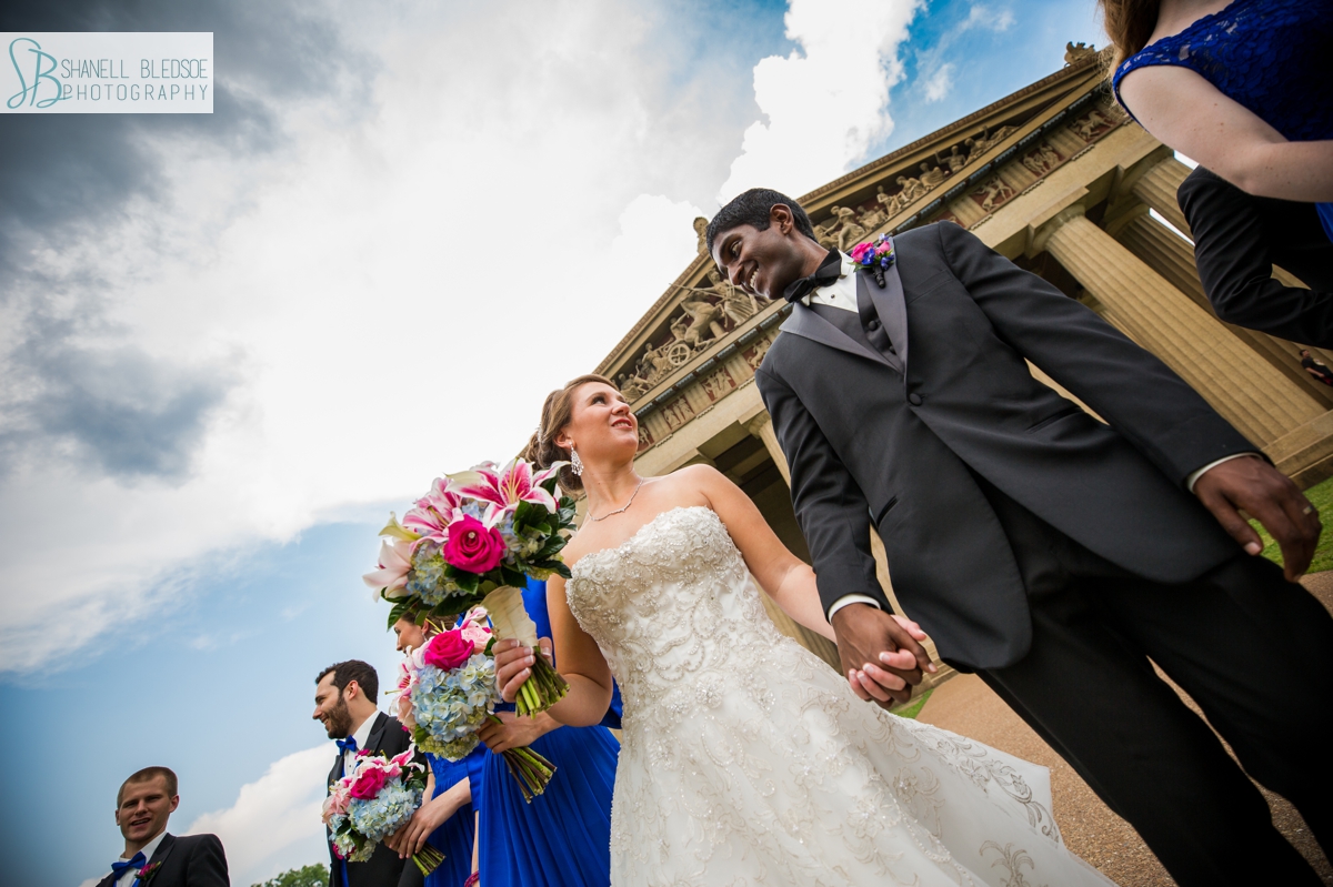 royal blue wedding party walking in front of the Parthenon in Nashville