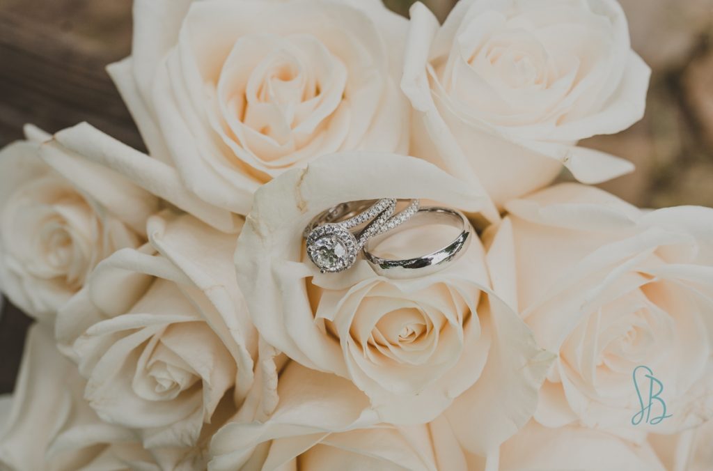 silver wedding rings on white roses