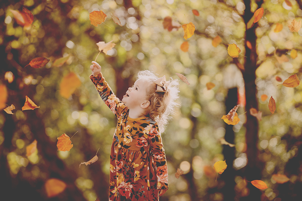 fall leaves falling around little girl