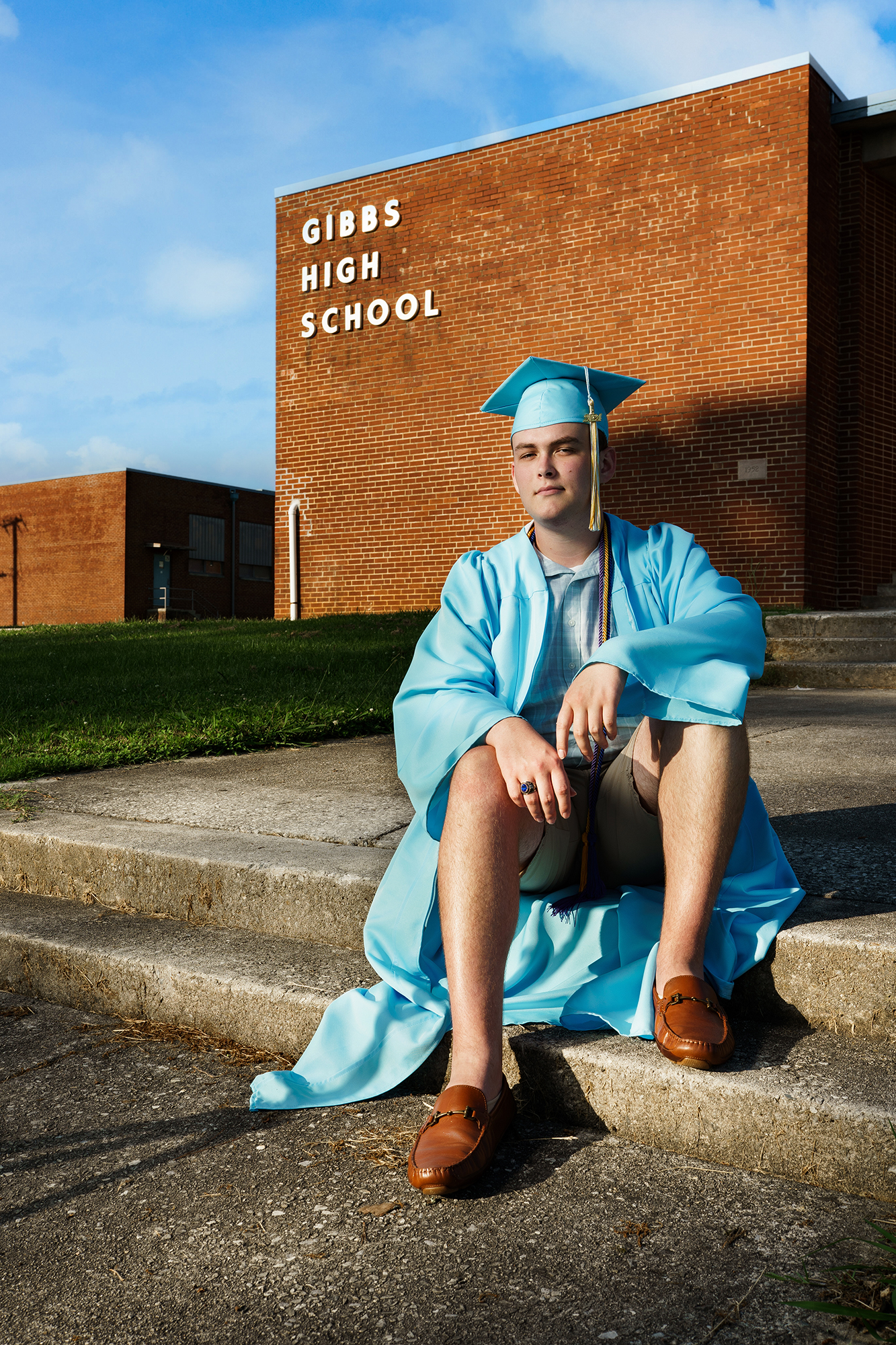 senior guy in cap and gown in front of Gibbs High School in Knoxville TN