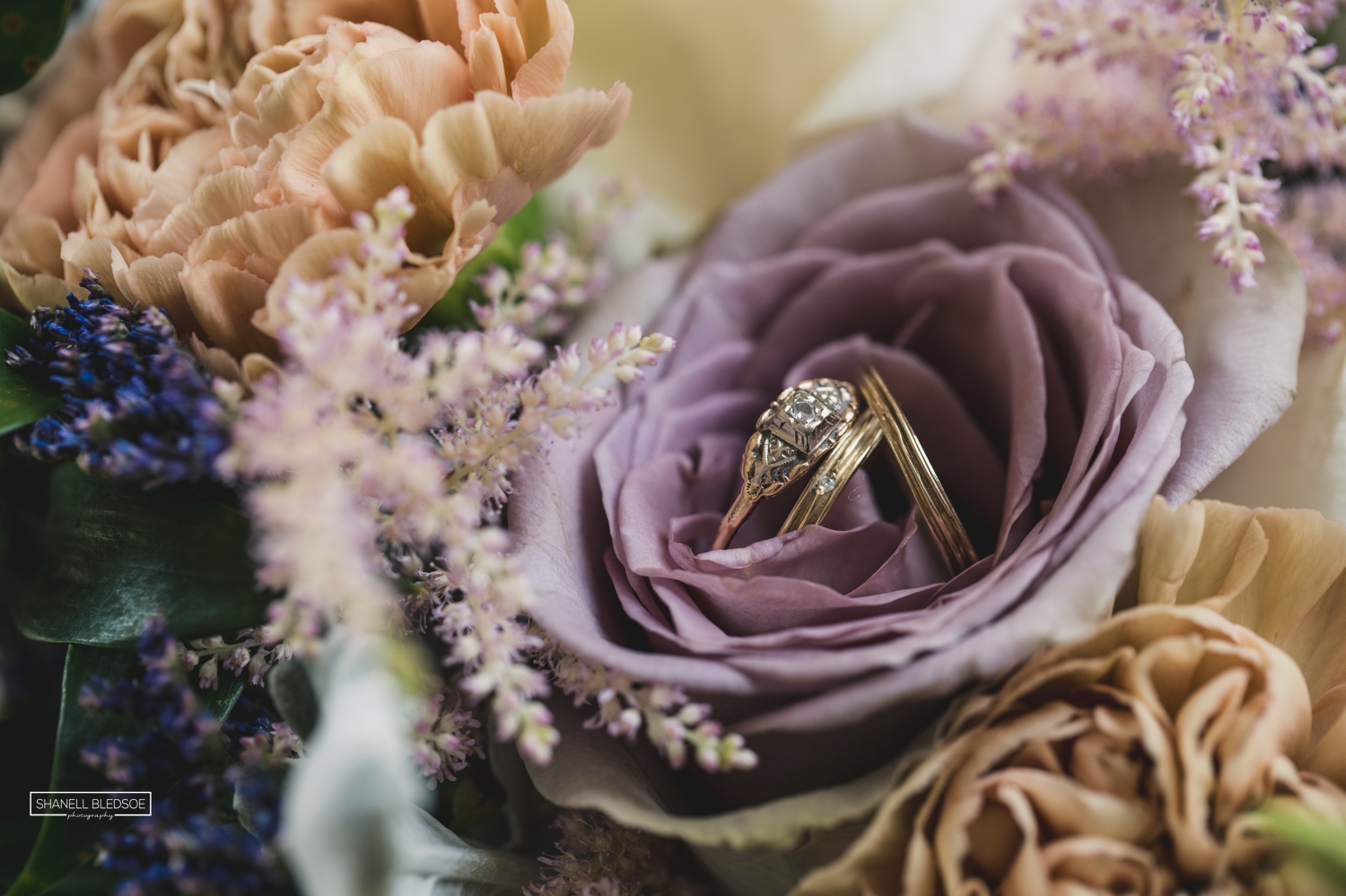 antique gold wedding rings inside lavender rose bouquet