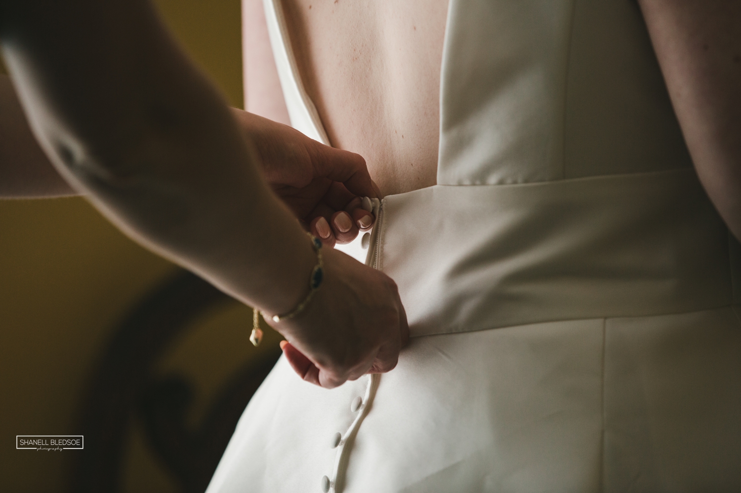 Zipping bride's dress by window light